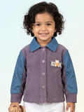 Young child wearing a purple ribbed corduroy button-down shirt with blue denim sleeves and a small teddy bear accent on the chest.