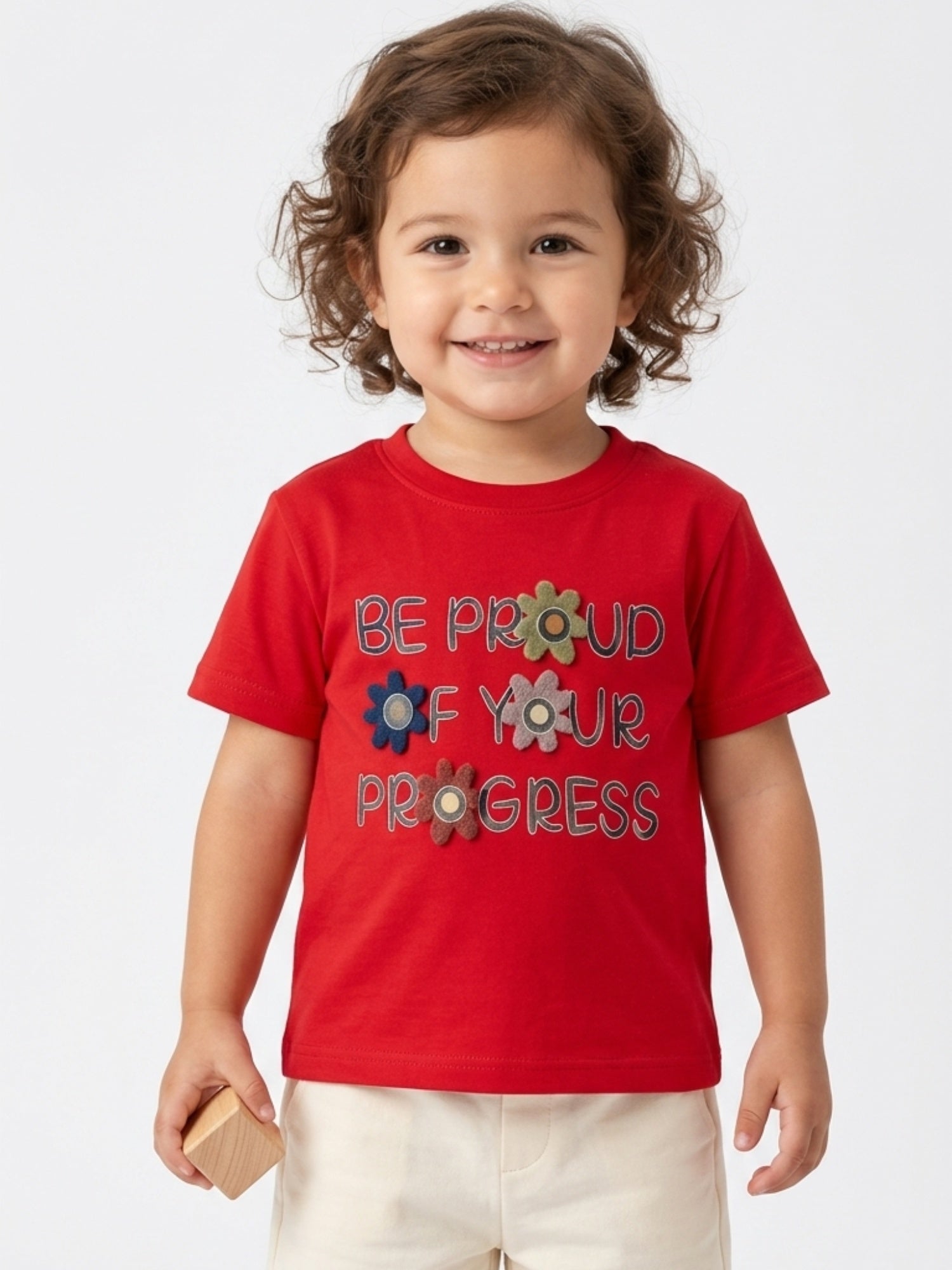 Toddler girl wearing a bright red short-sleeve t-shirt with "Be Proud Of Your Progress" text and felt flower accents.