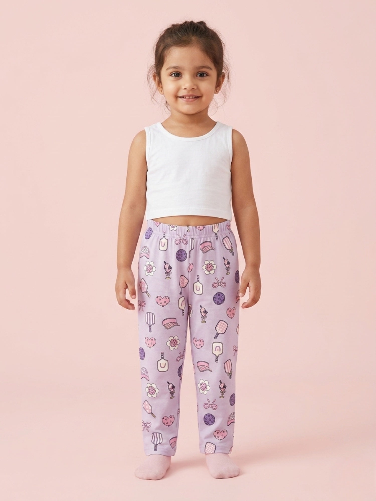 Girl in lavender cotton pajama pants with a purple heart and sports racket print pattern.
