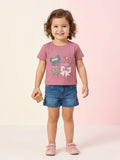A young girl wearing a vibrant magenta short-sleeve button-down shirt featuring double-ruffle sleeves with lace trim and a large matching floral lace appliqué on the chest.