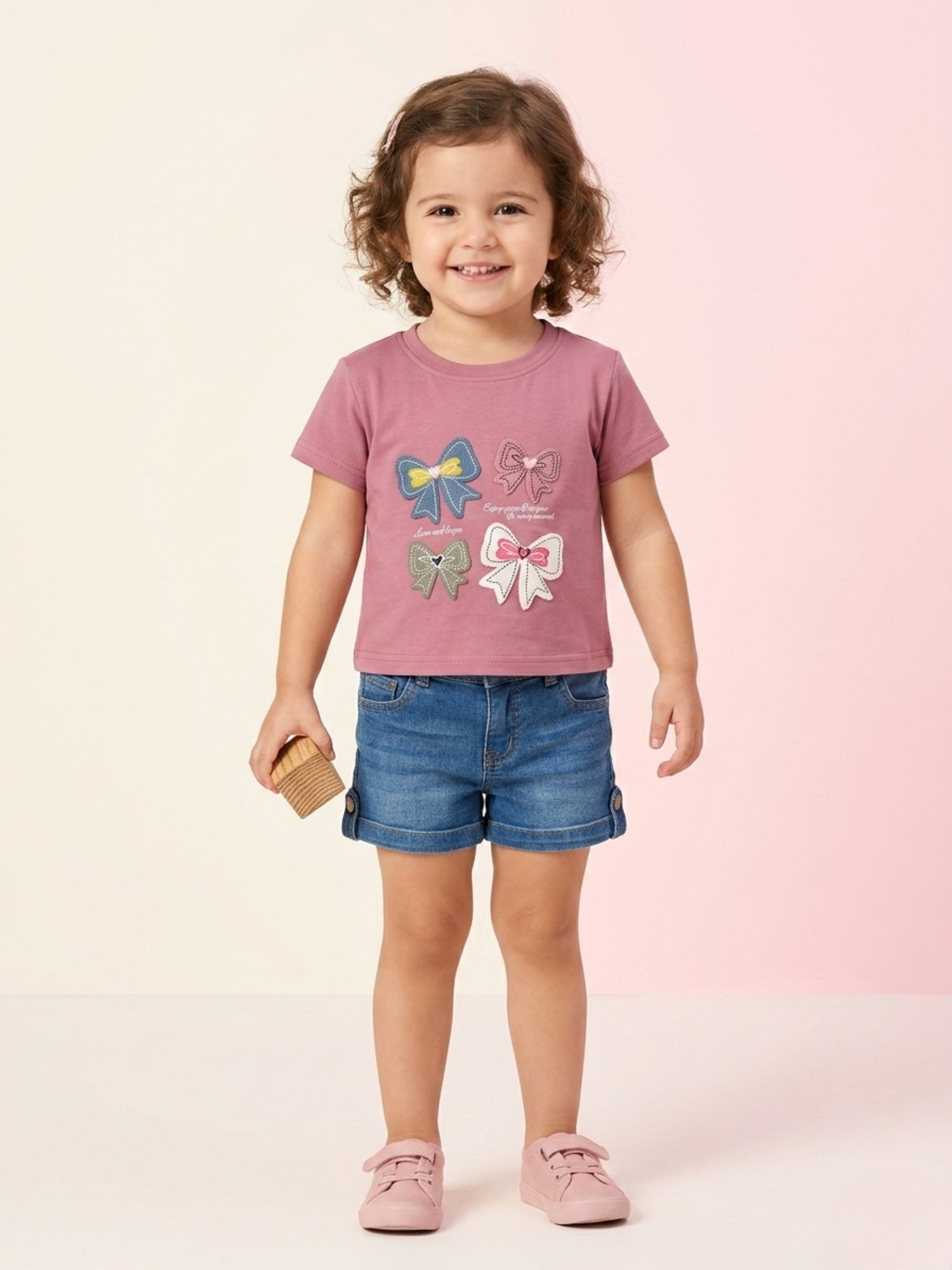 A young girl wearing a vibrant magenta short-sleeve button-down shirt featuring double-ruffle sleeves with lace trim and a large matching floral lace appliqué on the chest.