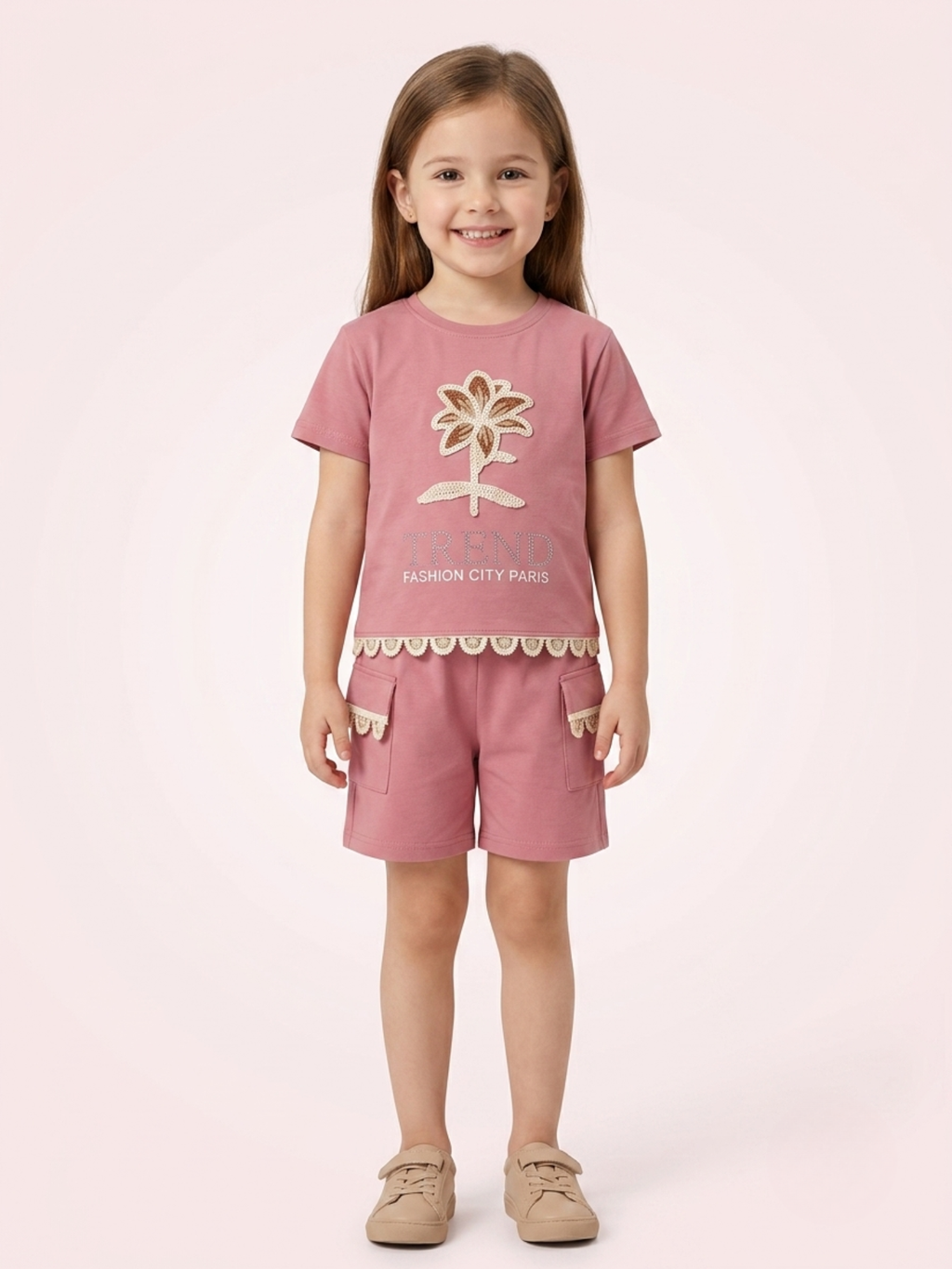 a smiling young girl wears a dusty onion pink short-sleeve t-shirt featuring a matching floral appliqué and scalloped lace trim along the hem and cargo pockets.