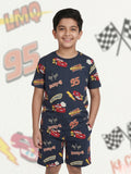Young boy smiling with hands in pockets wearing a dark grey two-piece cotton set with an all-over Lightning McQueen racing car and checkered flag print.