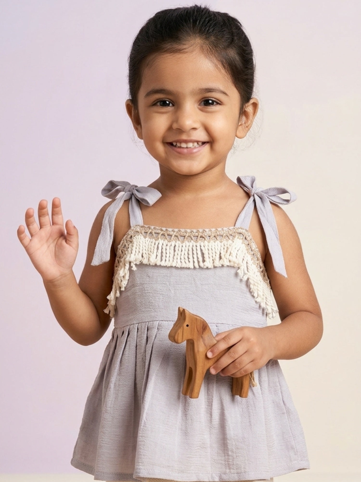 Young girl in a lilac/grey sleeveless top featuring white fringe detailing and adjustable tie-up shoulder straps.