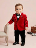 Cute baby boy in a vibrant red velvet blazer with a black waistcoat, black trousers, and a silver designer lapel brooch.