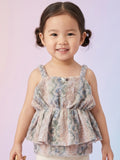 Little girl wearing a multicolor pastel textured peplum top with a butterfly brooch and white leggings.