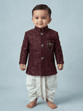 Little boy wearing a maroon sequin velvet sherwani with a traditional cream dhoti.
