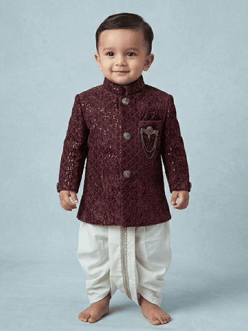 Little boy wearing a maroon sequin velvet sherwani with a traditional cream dhoti.