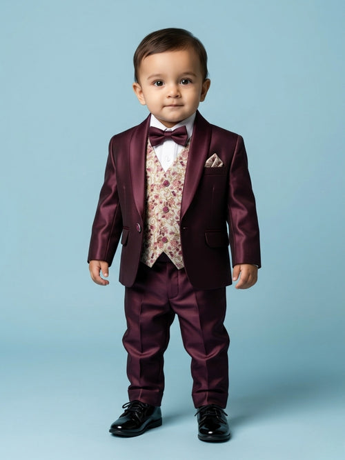 1-year-old baby boy in a luxury wine-colored silk tuxedo featuring a cream floral jacquard waistcoat and matching bow tie.