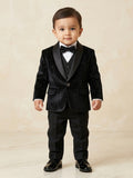 Baby boy posing in a luxury black shimmer tuxedo with glitter texture and black satin shawl lapels for a formal party.