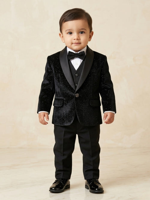 Baby boy posing in a luxury black shimmer tuxedo with glitter texture and black satin shawl lapels for a formal party.