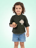 Young girl wearing an olive green mandarin collar shirt with a large leaf applique and a delicate scalloped bottom edge.