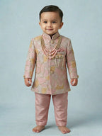 Toddler boy wearing a rose pink designer sherwani with a traditional embroidered dhoti.