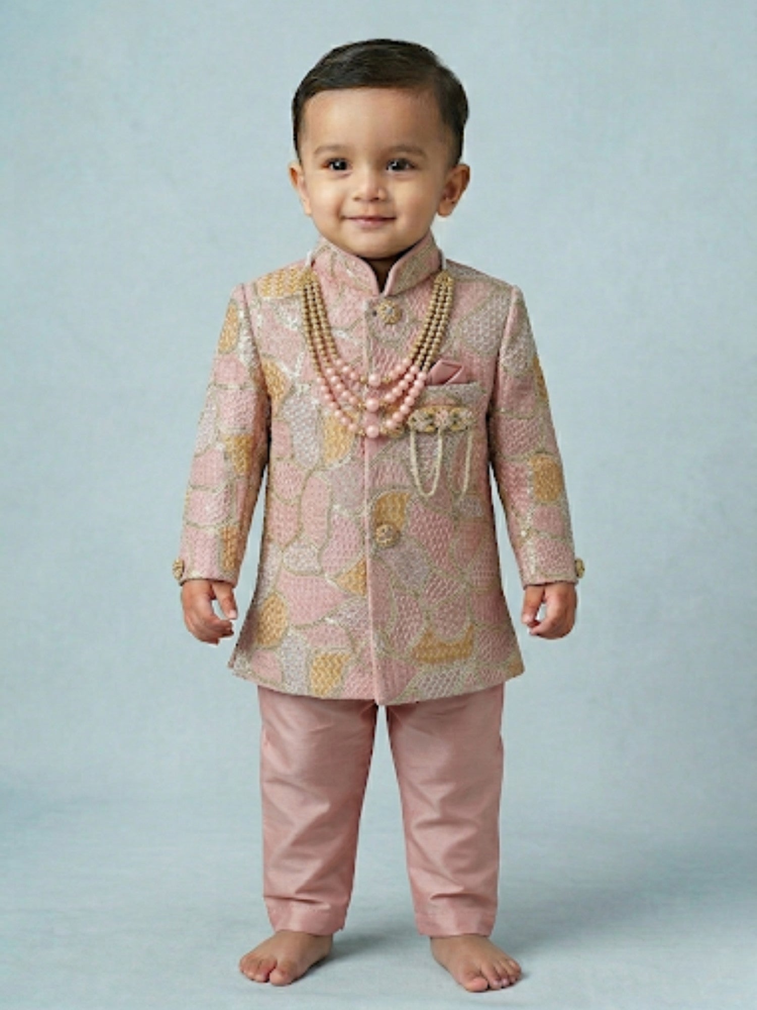 Toddler boy wearing a rose pink designer sherwani with a traditional embroidered dhoti.