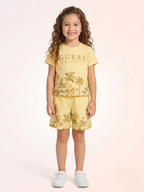 a young girl with long curly hair wears a soft yellow knit t-shirt and elastic-waist shorts set featuring golden-brown palm tree landscape graphics.