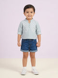 A toddler girl with curly hair wearing a deep teal short-sleeve button-up top with white vertical lace trim and a matching white lace collar.