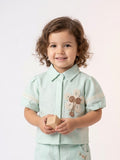 Young girl wearing a mint green short-sleeve shirt with puff sleeves and a large cream crochet flower patch.