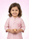 Little girl in a blush pink silk kurta featuring a large floral applique on the chest and embroidered sleeve details.