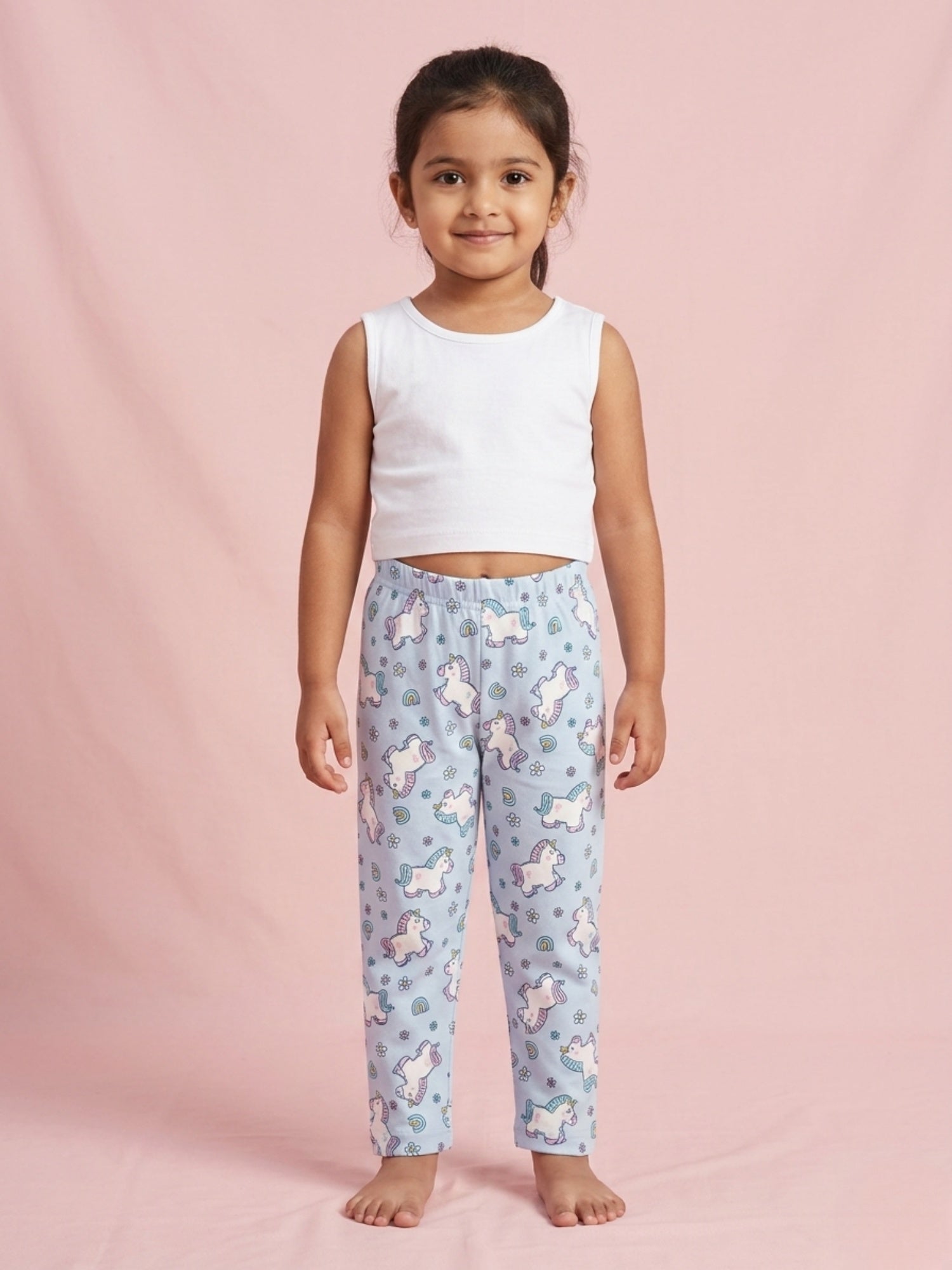 Little girl wearing sky blue cotton pajama pants with a colorful unicorn and rainbow pattern